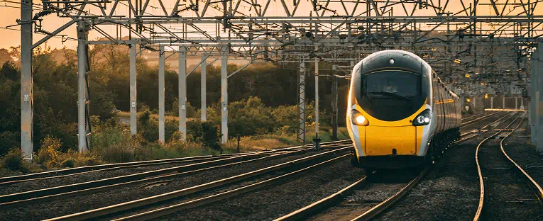 A train traveling along the tracks, showcasing its sleek design against a backdrop of greenery.