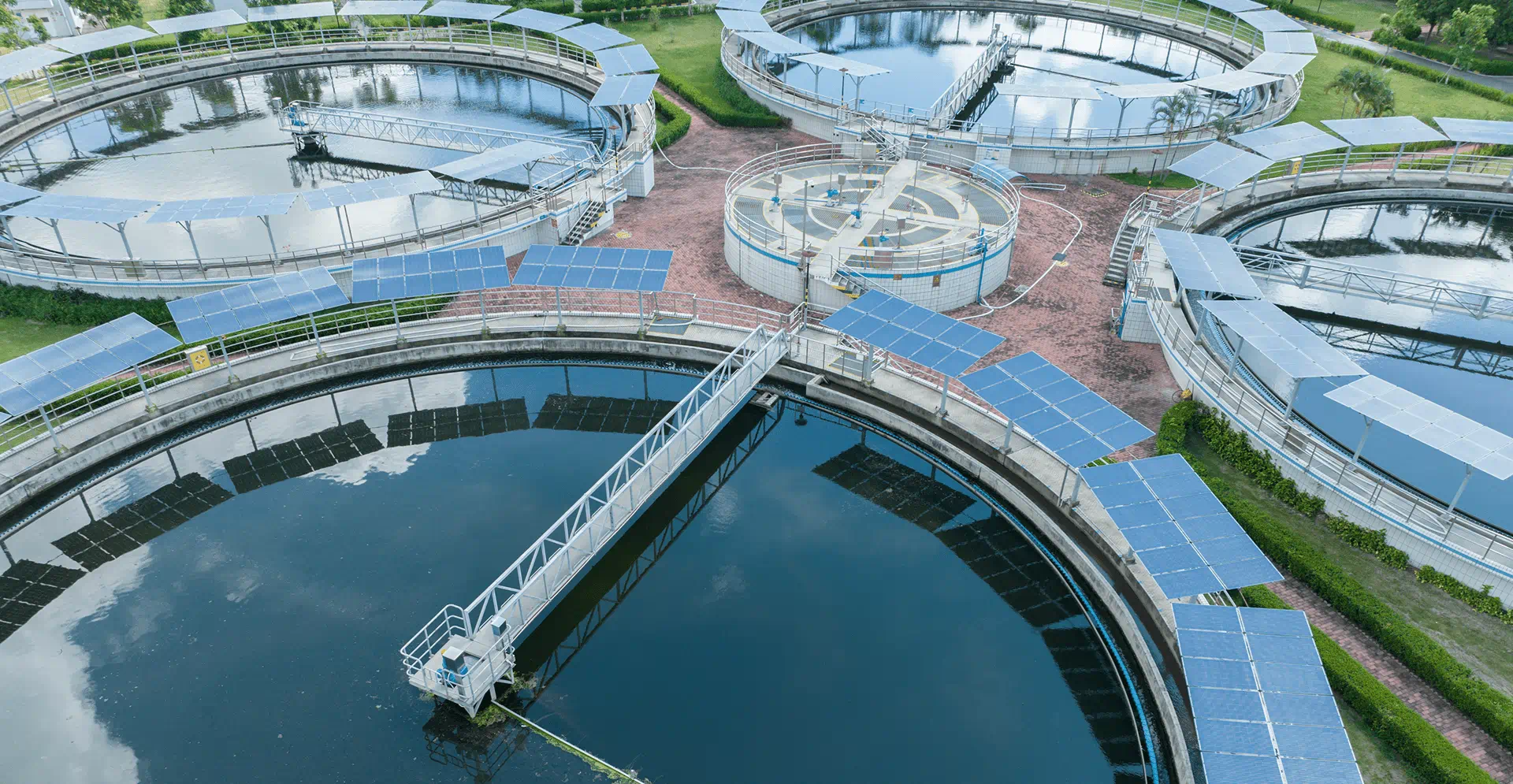 Aerial perspective of a water treatment facility with multiple tanks and processing areas, set in a natural landscape.