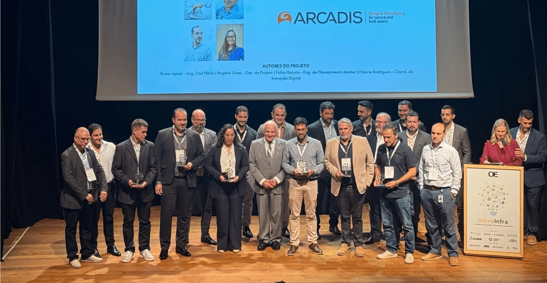 A group of people on stage proudly holding their awards, smiling and celebrating their achievements together.