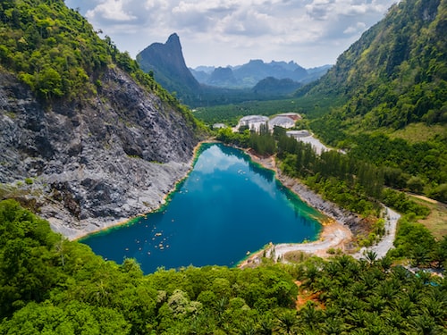Turquoise lake in lush mountains with rocky cliffs and forest valley.