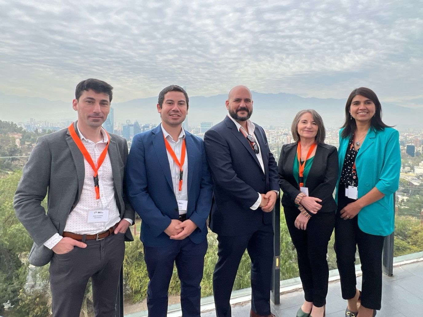 Business team of five individuals with cityscape in background.