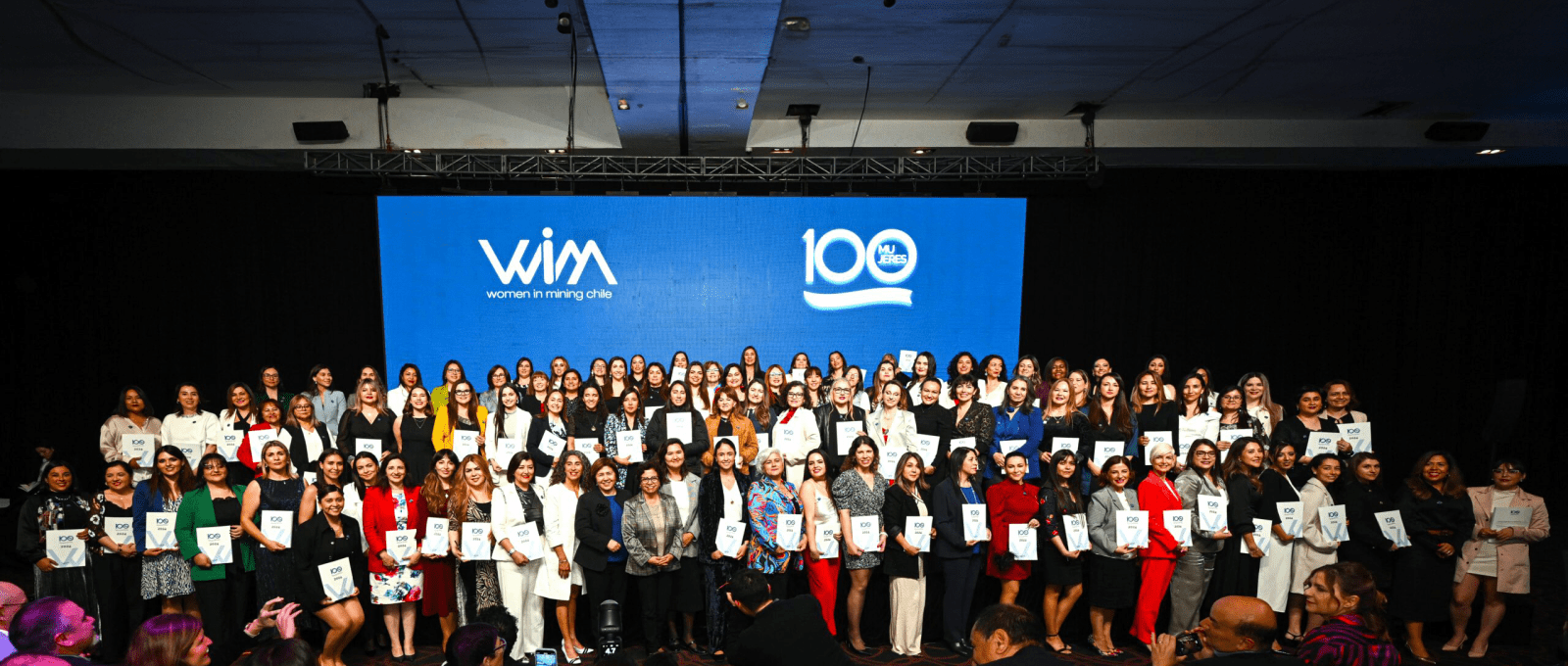 A diverse group of women standing together on stage, showcasing their awards, representing empowerment and accomplishment.