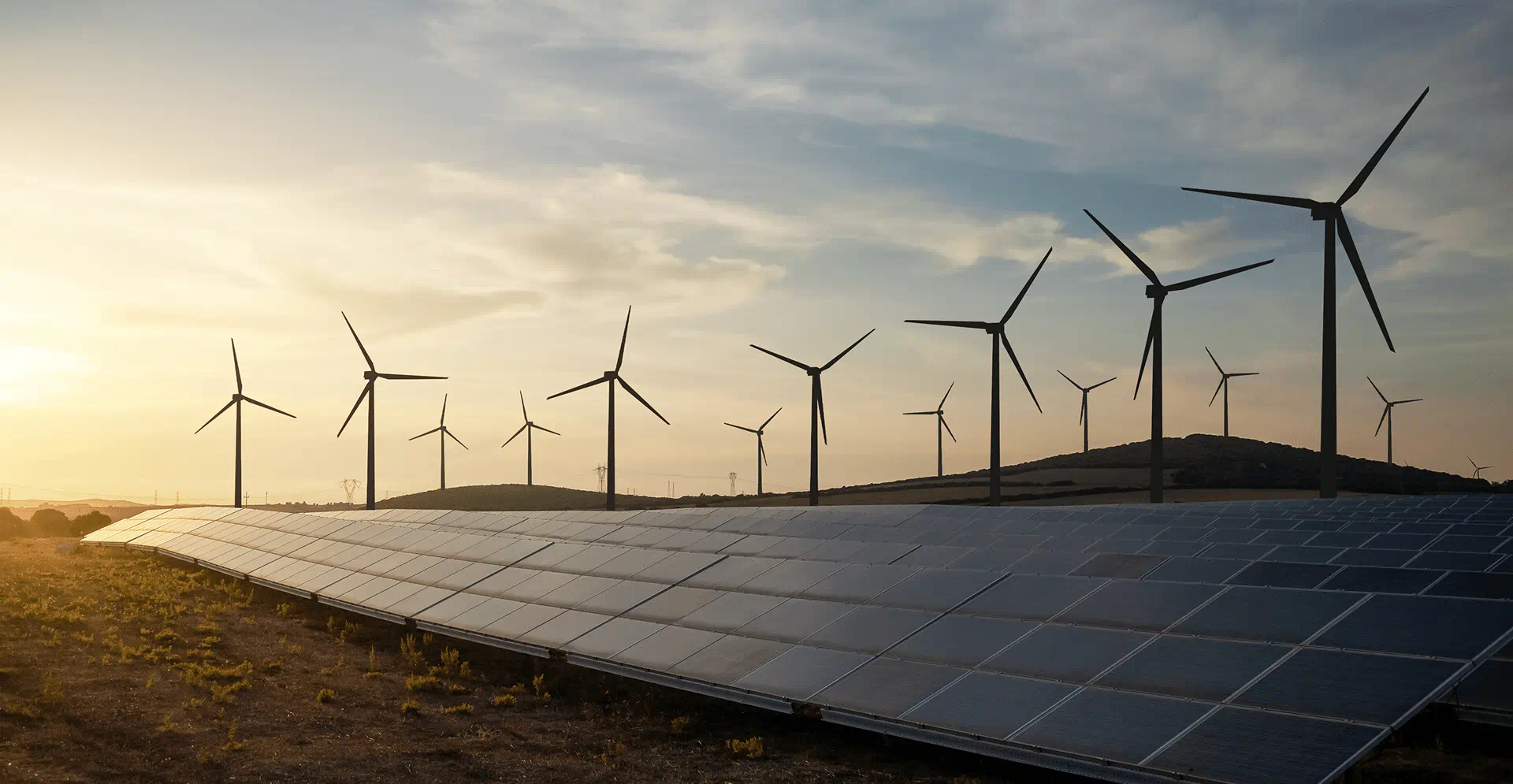 Solar panels and wind turbines silhouetted against a vibrant sunset sky, highlighting renewable energy sources.