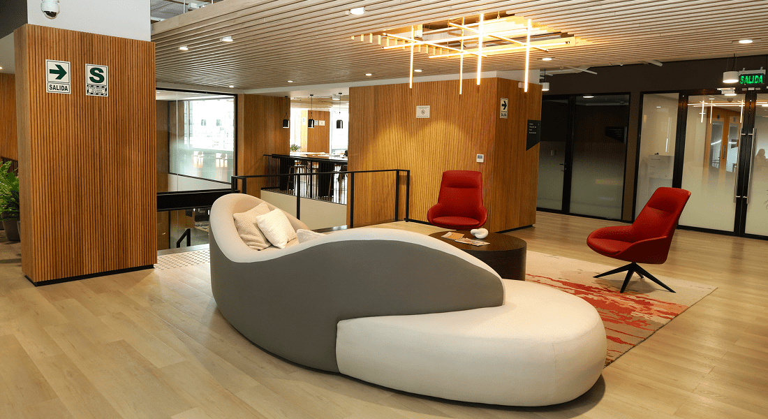A modern office featuring a curved couch and stylish chairs arranged for a collaborative workspace.