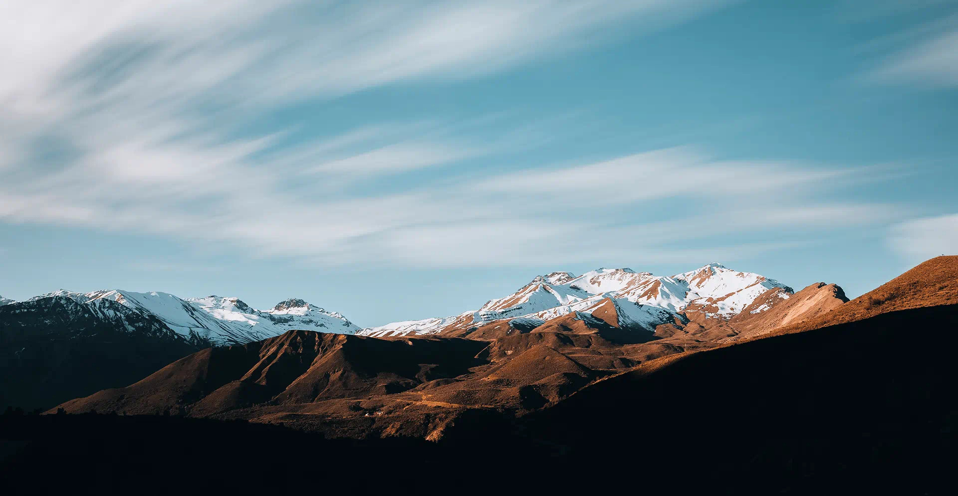 Scenic mountain landscape with snow-covered peaks and dramatic sky, showcasing natural beauty, outdoor adventure, and sustainable environment themes.