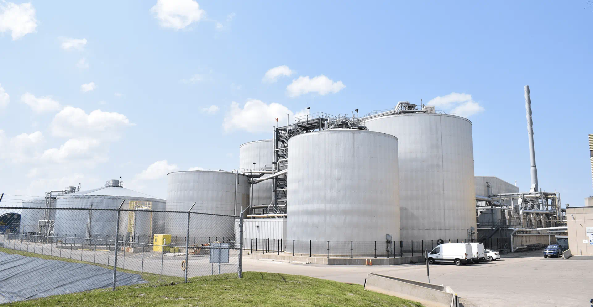 A large industrial plant featuring multiple tanks surrounded by a security fence.