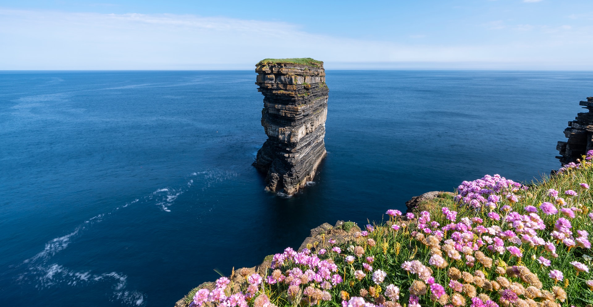 A massive rock formation rises dramatically, highlighting its unique shapes and textures in a serene outdoor setting.