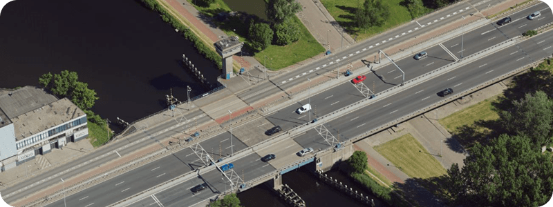  An aerial perspective of a bridge crossing a river, highlighting the flowing water and natural landscape surrounding it.
