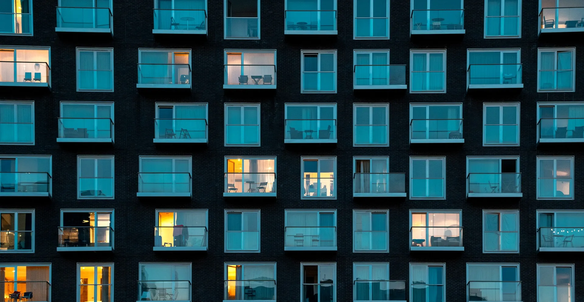 A multi-story building illuminated by numerous windows, showcasing a vibrant display of lights at night.