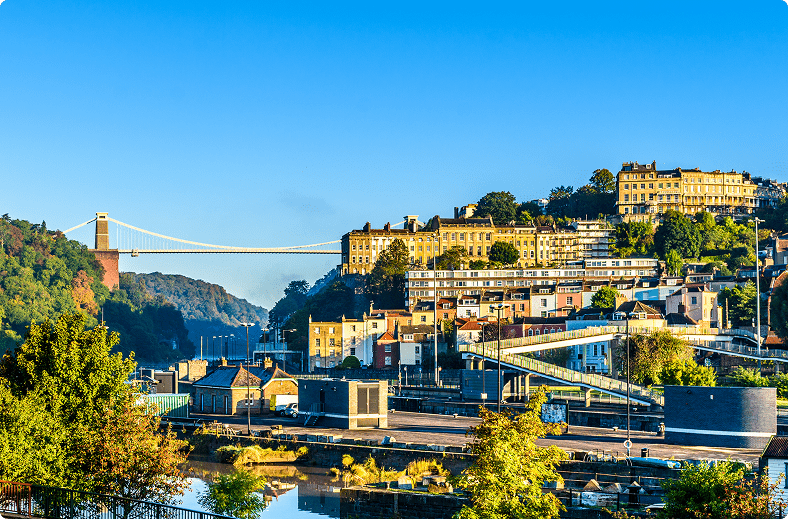A scenic bridge spanning a river, surrounded by lush greenery and clear blue skies.