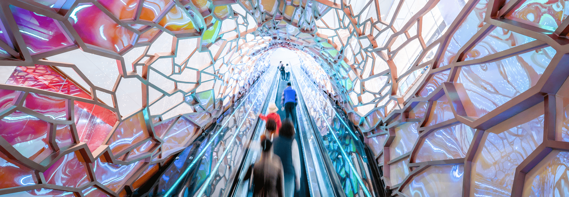 A vibrant tunnel filled with colors, featuring people walking through, creating a lively and dynamic atmosphere.