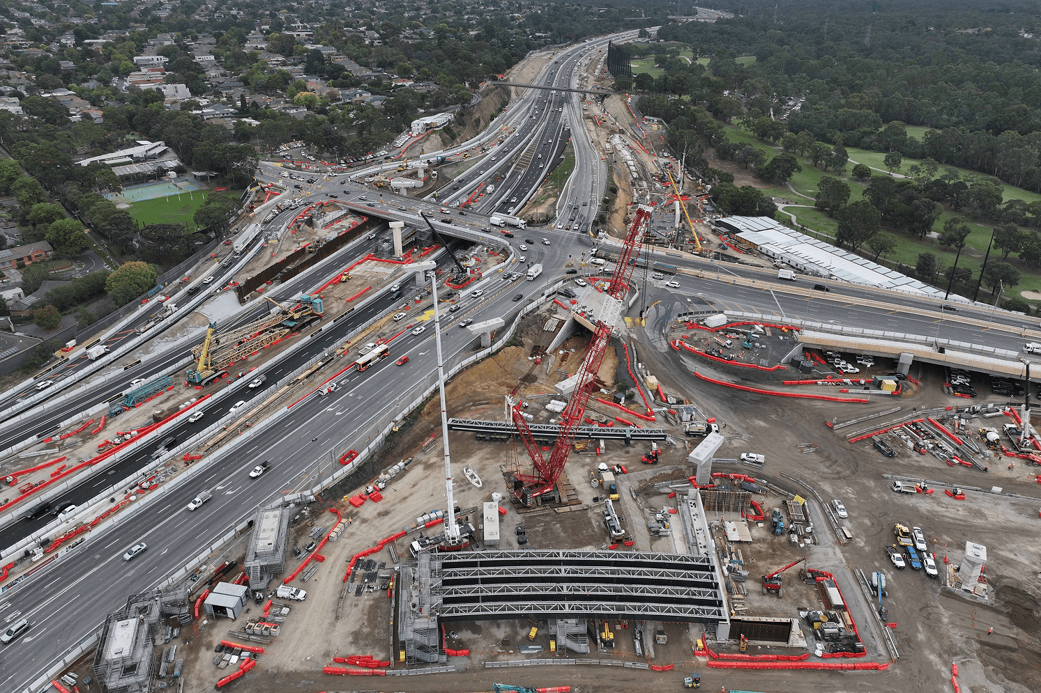 Aerial view of a highway construction site, showcasing machinery, workers, and ongoing road development activities.