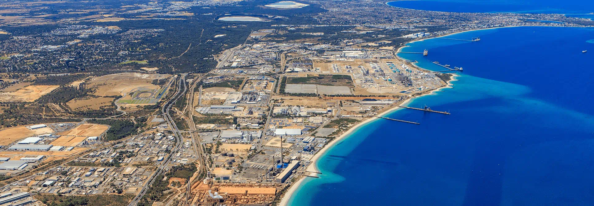 Aerial view showcasing a vibrant city skyline adjacent to a sandy beach and clear blue ocean waters.