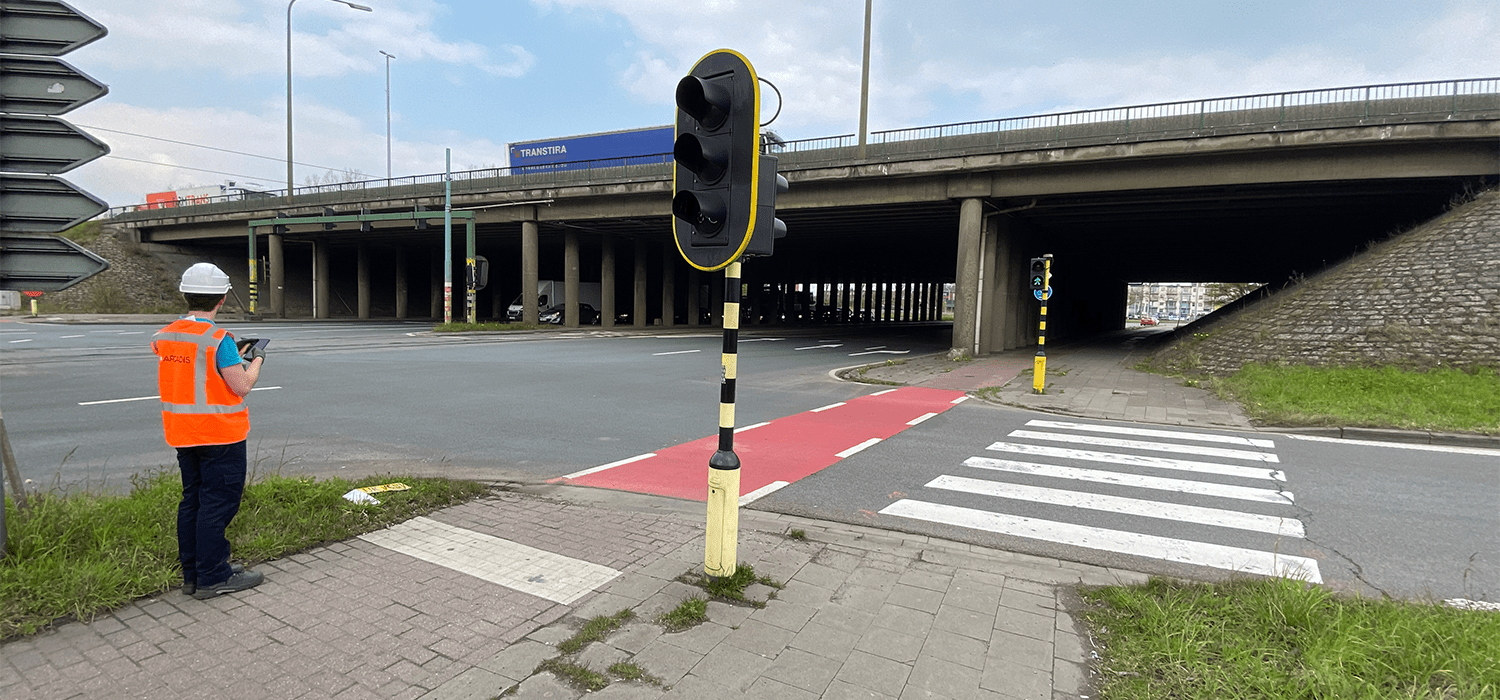 An Arcadis expert wearing a helmet and fluorescent vest inspects the abutment of a bridge. 