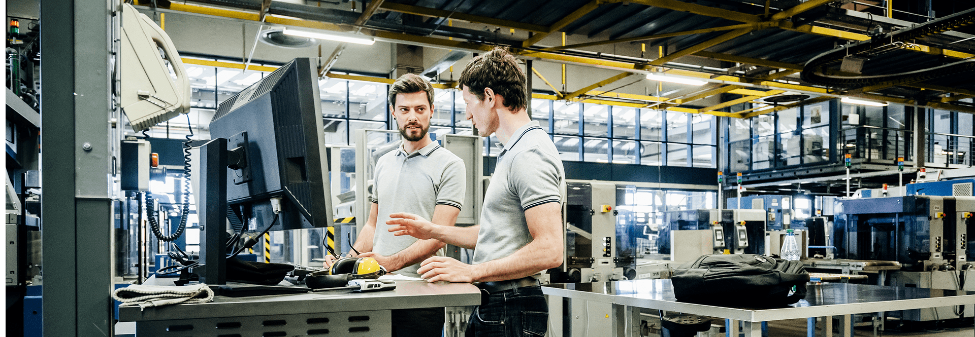 Deux ingénieurs effectuant des calculs sur un écran dans un contexte industriel.