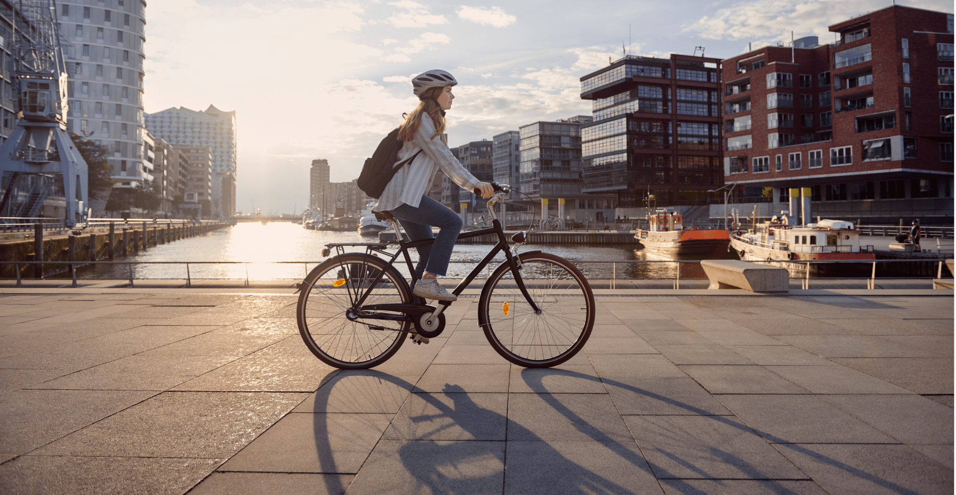A woman cycling on a city street, surrounded by urban scenery and buildings, showcasing an active lifestyle.