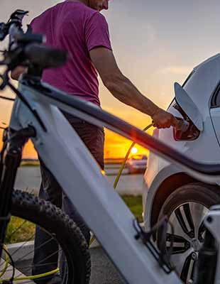 Mann steckt elektrischen Stecker in Auto zum Aufladen