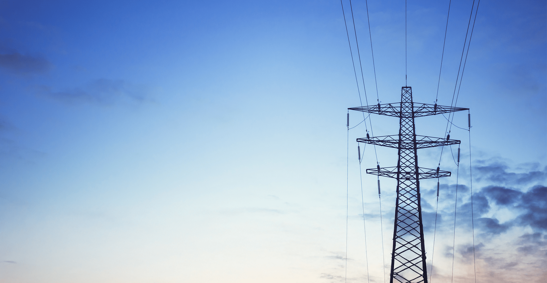 High voltage power lines and electricity towers silhouetted against a clear blue sky, showcasing energy infrastructure.