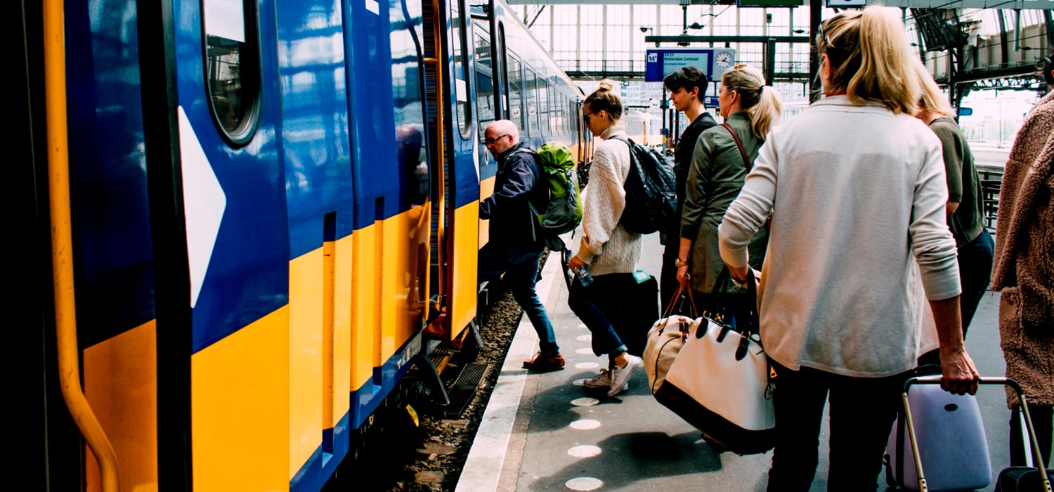 Reizigers die in een blauw gele trein van de NS stappen
