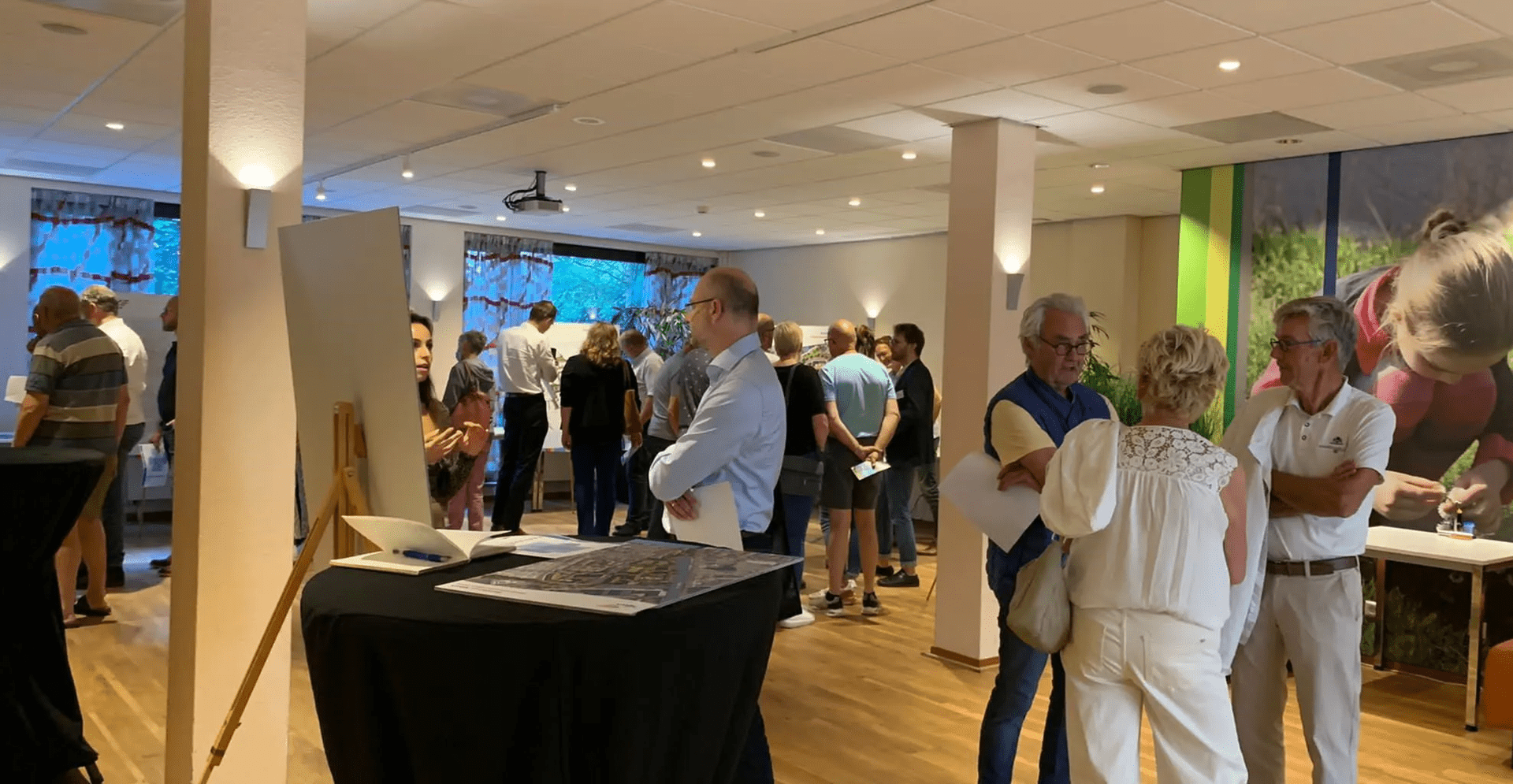 People gathered in room with colorful mural in background.