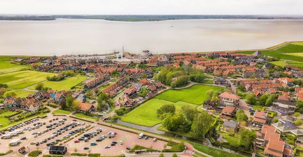 Luchtfoto van deel van de  Markermeerdijken met dorpje aan het water.