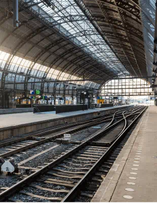 A train station featuring a train on the tracks, surrounded by platforms and waiting passengers.