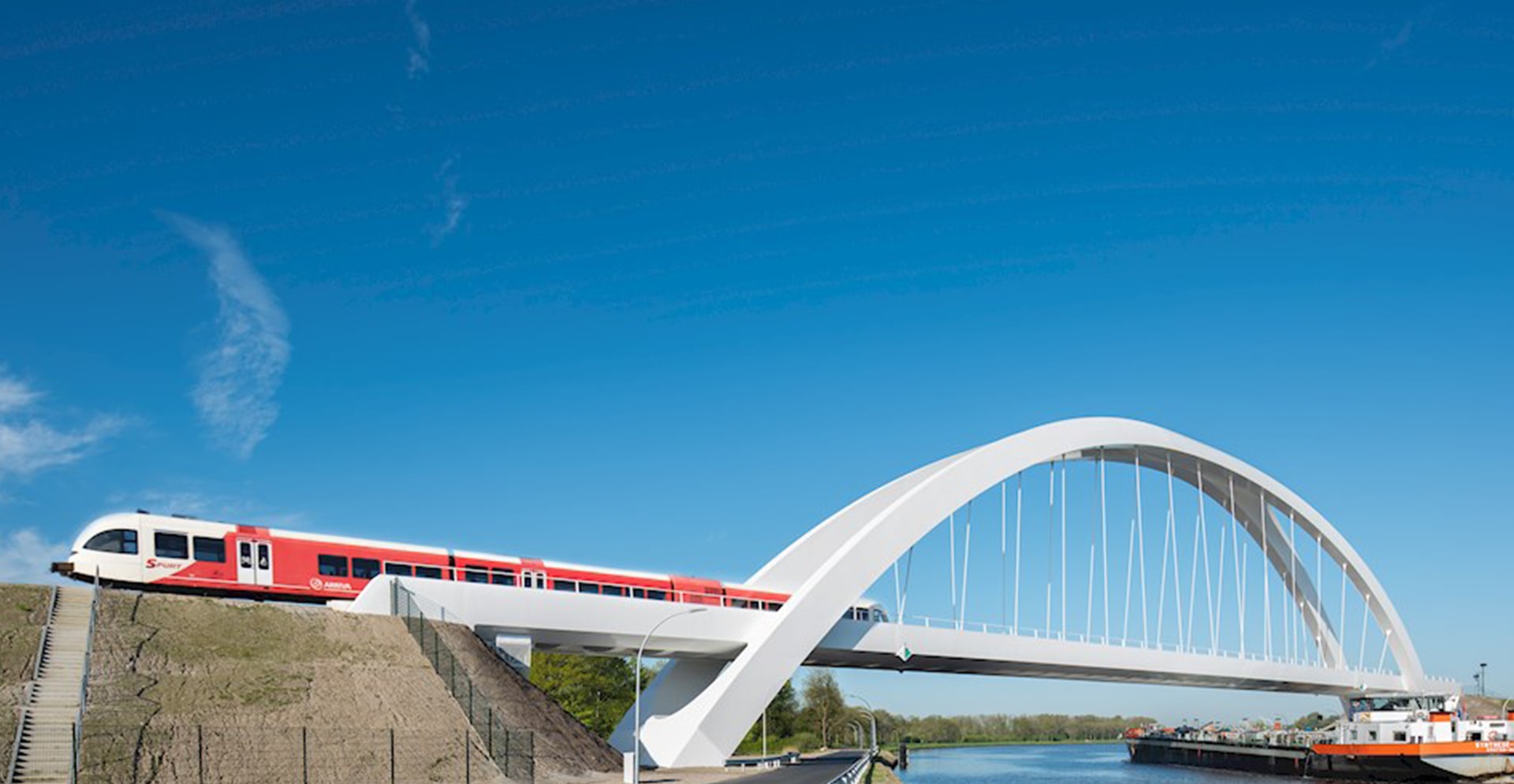 Nieuwe witte spoorbrug bij Zuidhorn vanaf de zijkant bekeken op het moment dat er een trein net overheen is.