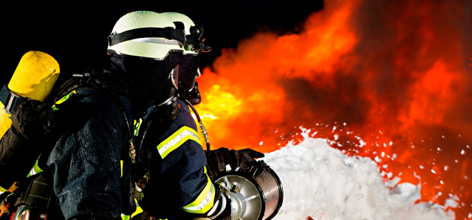 Brandweerman die vlammenzee probeert te blussen met blusschuim