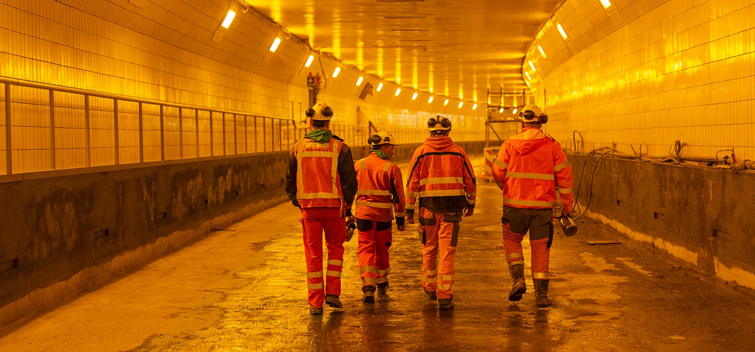 Vier bouwvakker lopen de tunnel in om aan het werk te gaan.