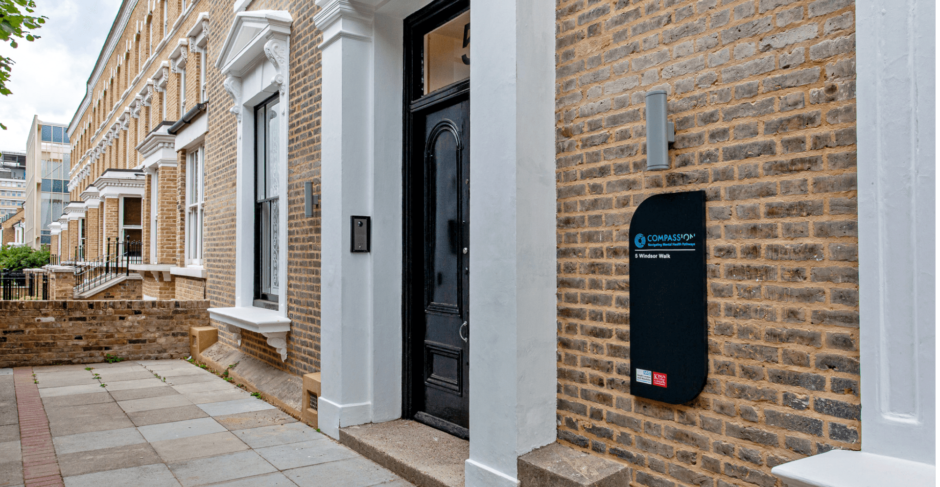A brick building with a door and a sign on it.