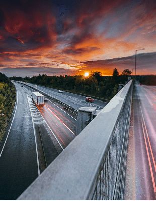 Sunset over a highway, showcasing cars in motion against a backdrop of warm, glowing hues.