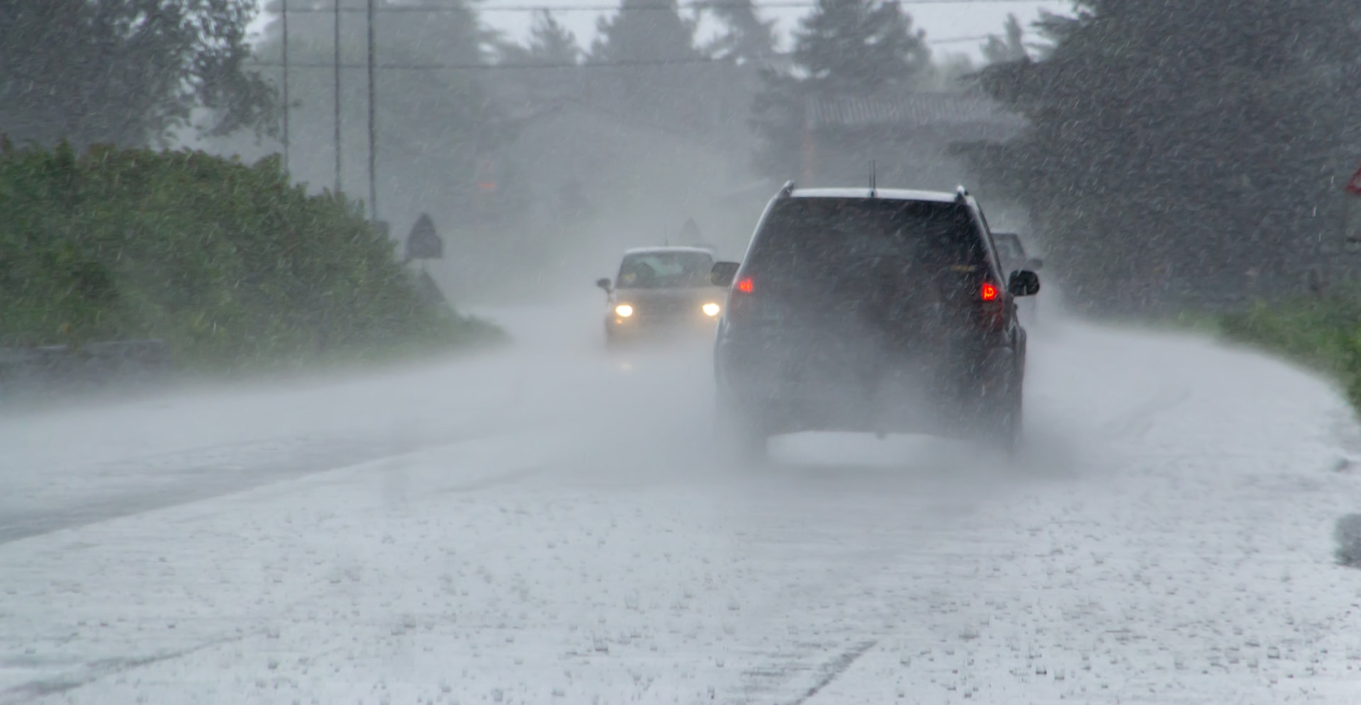 The strong storm with heavy rain on the road with poor visibility of cars. Concept of the danger of driving in bad weather