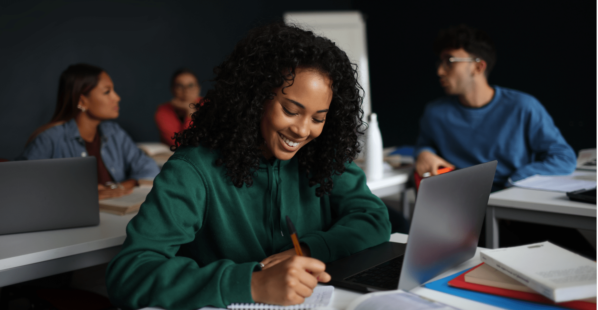 A woman smiles while focused on her laptop, showcasing a positive and productive work environment.