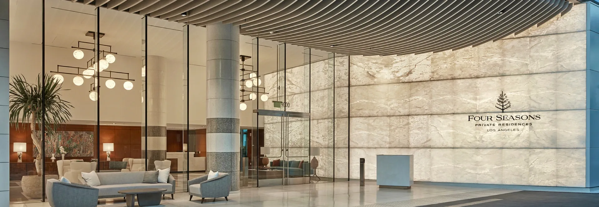 A modern hotel lobby featuring a spacious design with a large glass wall, allowing natural light to illuminate the space.