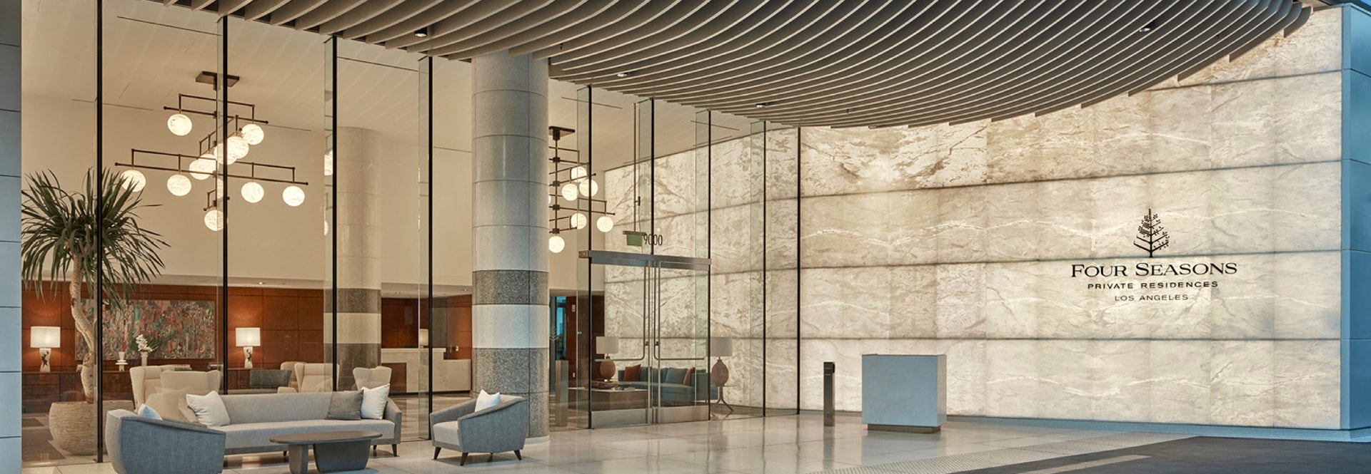 A modern hotel lobby featuring a spacious design with a large glass wall, allowing natural light to illuminate the space.