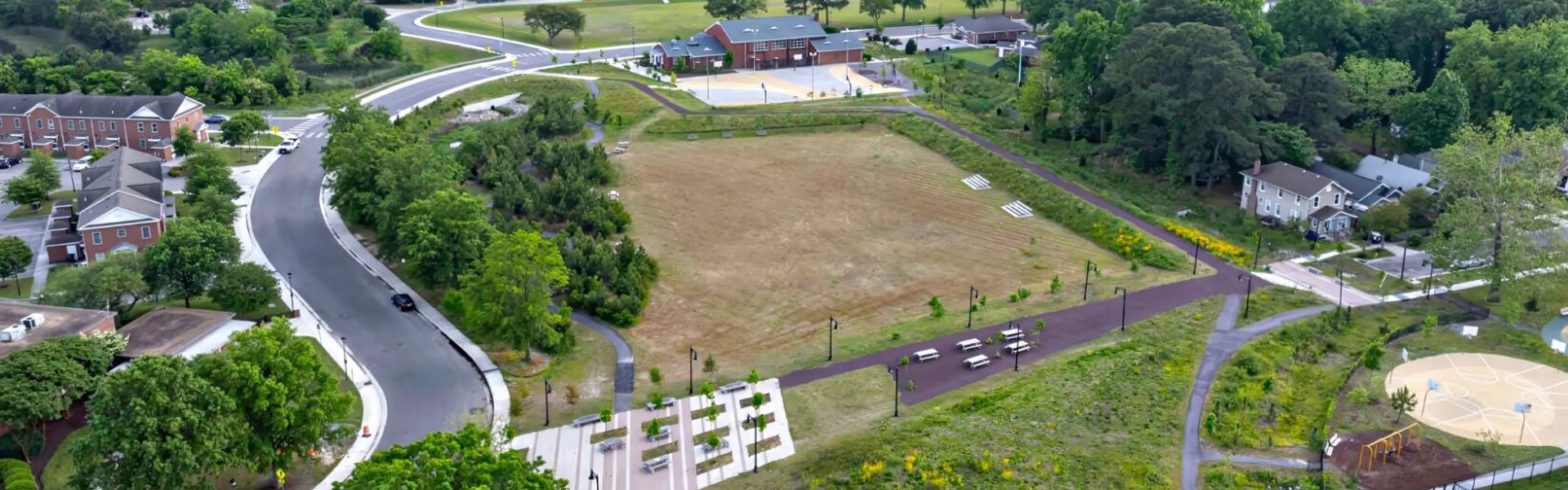 Aerial view of a park featuring a playground surrounded by green trees and open spaces.